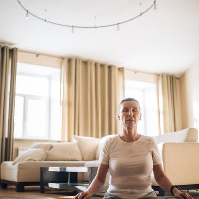 A person sitting calmly on a yoga mat with eyes closed.