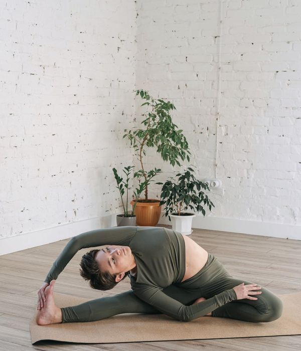 Woman in a simple yoga pose in a minimalist, light-filled room.